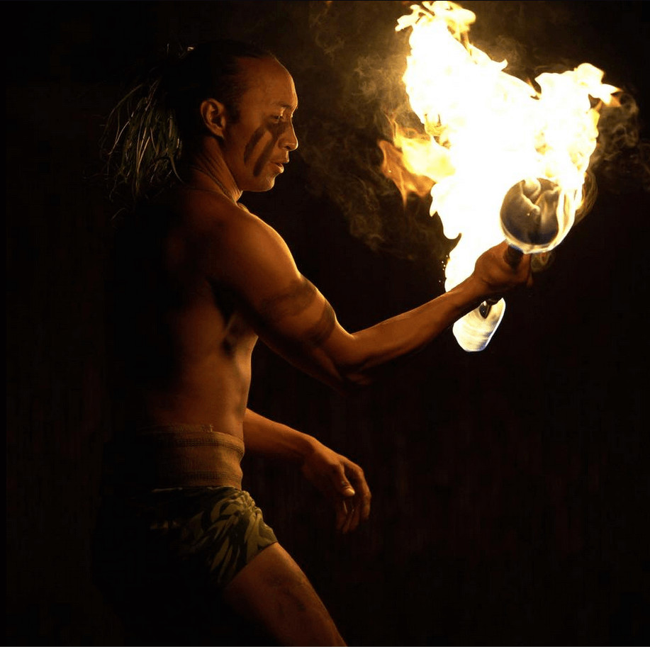An Island Breeze Luau fire dancer holding flaming torches